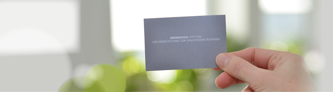 Eine Hand hält eine Visitenkarte der "Grünenthal-Stiftung zur Unterstützung von Thalidomidbetroffenen"